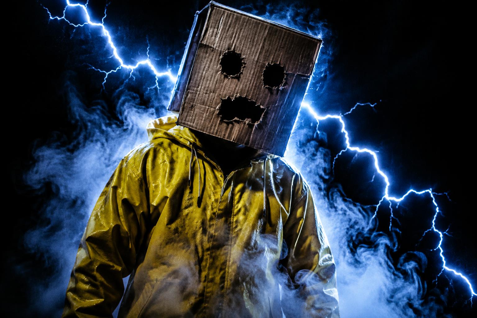 A figure in a yellow raincoat with a cardboard box on their head, surrounded by lightning